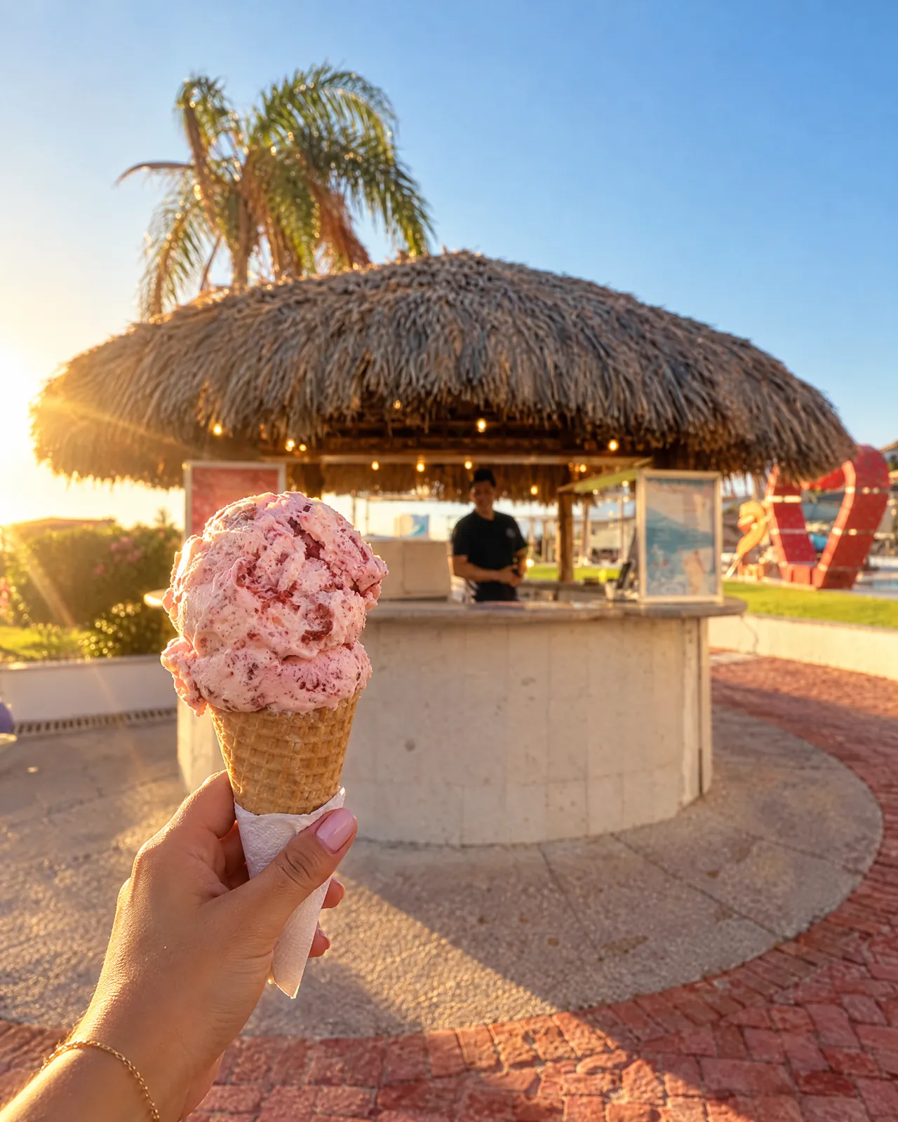 Cono de nieve de fresa frente a la palapa Splash al atardecer